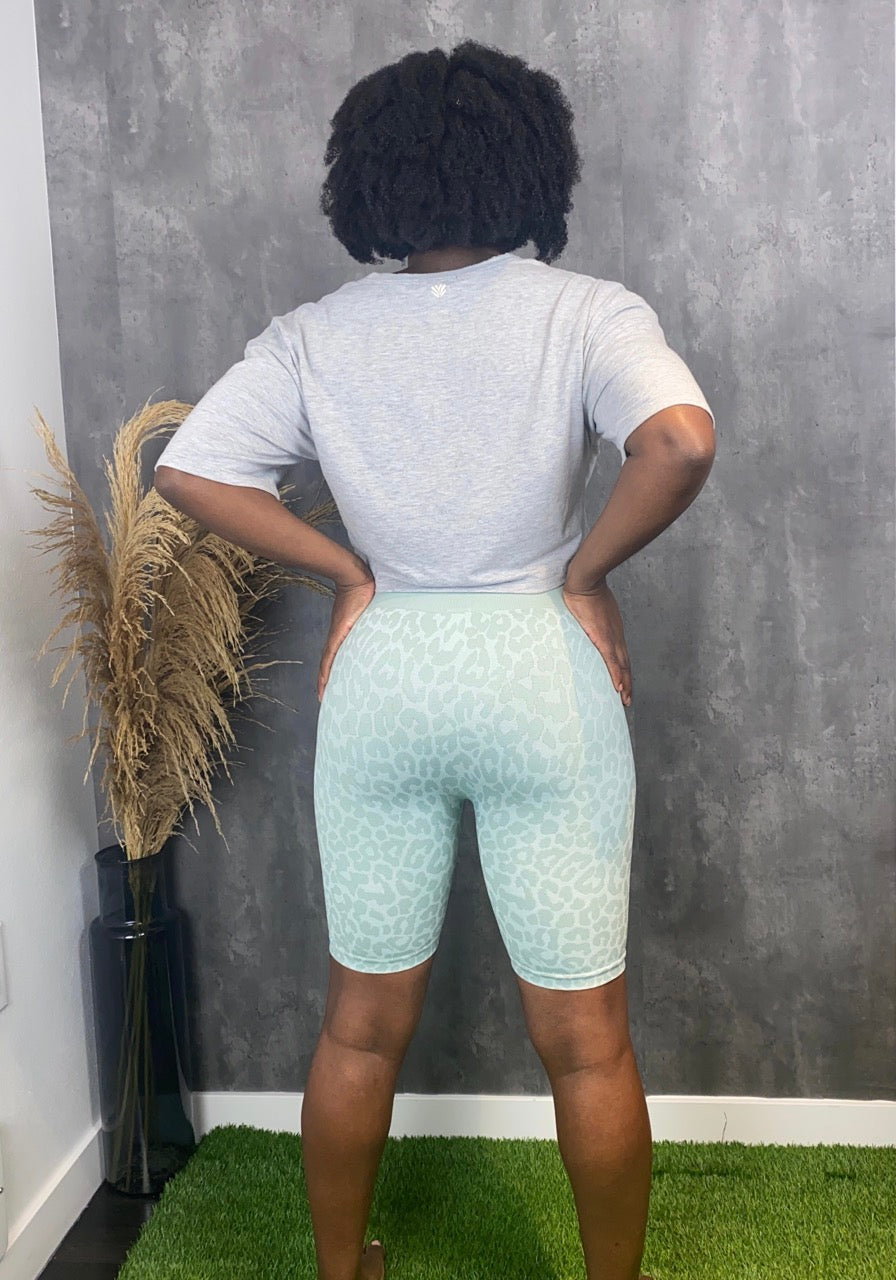 The high-waisted biker shorts are designed with a seamless monochromatic leopard print design in the color aqua.